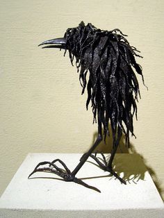 a sculpture of a black bird with long legs and feathers on it's head