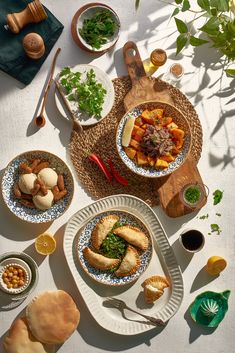 a table topped with plates and bowls filled with different types of food next to utensils