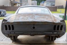 an old rusty car is parked on the sidewalk