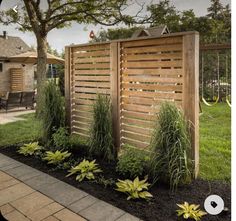 a wooden fence in the middle of a yard with flowers and plants growing around it