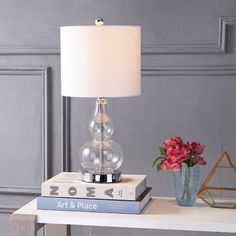 a lamp sitting on top of two books next to a vase with flowers