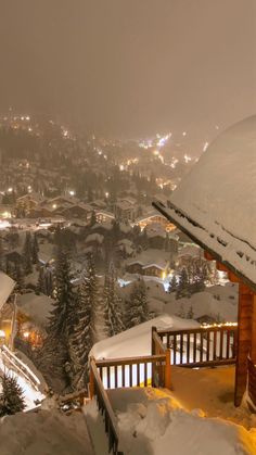 a snowy night in the mountains with lights on and snow covered trees, houses and buildings