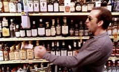 a man standing in front of a shelf filled with bottles