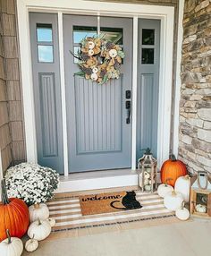 the front door is decorated with pumpkins and flowers