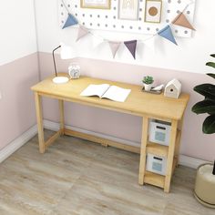 a desk with a book, lamp and potted plant in front of the wall