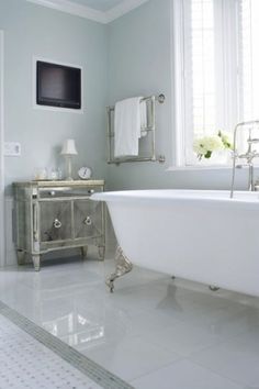 a white bath tub sitting in a bathroom next to a tv mounted on the wall