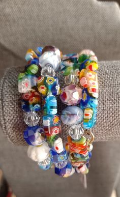 a person wearing a bracelet made out of glass beads and other colorful items on their arm