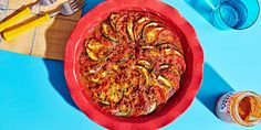 a pizza sitting on top of a red plate next to glasses and utensils