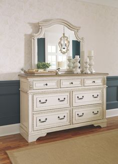 a white dresser with a mirror on top of it next to a rug and window