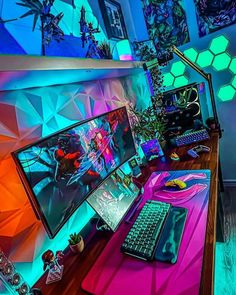 a computer desk with a laptop, keyboard and monitor on it in front of a colorful wall