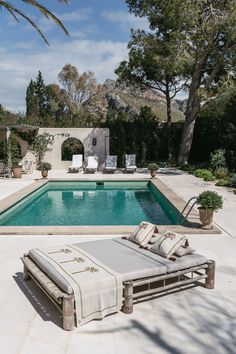 an empty pool with lounge chairs around it and trees in the backgrouds