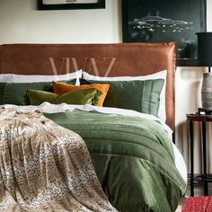 a bed with green comforter and pillows in a bedroom next to a night stand