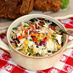 a white bowl filled with coleslaw and carrots on top of a red checkered table cloth