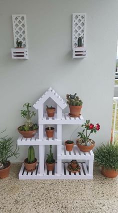 several potted plants are placed on top of a white house shaped shelf with succulents and cacti