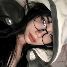 a woman with glasses is laying down under a blanket