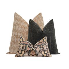 three pillows with decorative designs on them, one black and the other brown are sitting next to each other