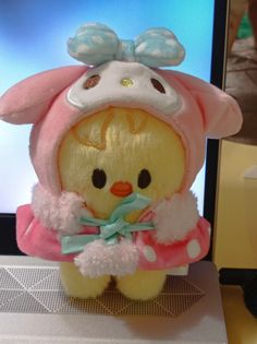 a stuffed animal with a pink outfit and bow on it's head sitting in front of a computer screen