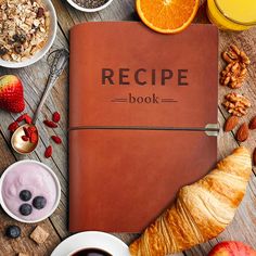 a recipe book surrounded by fruit, nuts and other foods on a wooden table with orange juice