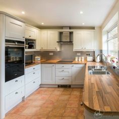 a kitchen with white cabinets and wooden counter tops