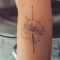 a tattoo on the leg of a woman with a flower and arrow in it's center