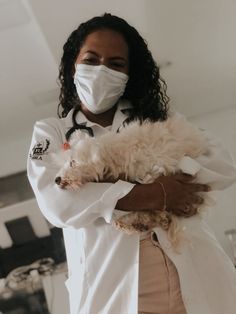 a woman wearing a face mask holding a dog