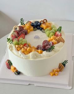 a white cake with fruit on it sitting on a plate