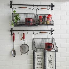 two metal racks holding pots, pans and utensils on a white brick wall