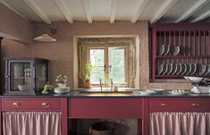 a kitchen with red cabinets and dishes on the counter