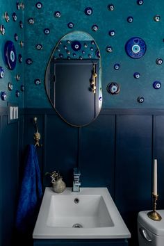 a bathroom with blue walls and gold accents on the wall, along with a white sink