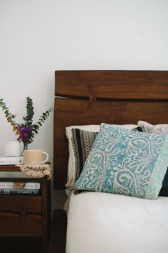 a bedroom with a bed, night stand and vases on the side table next to it