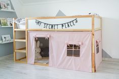 a child's bedroom with a pink tent bed and shelves on the wall next to it