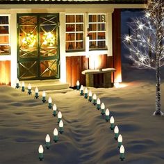 a house with christmas lights in front of it and snow on the ground next to it