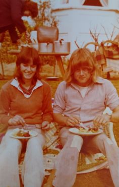 two women sitting on the grass eating food