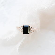 a black and white diamond ring sitting on top of a piece of fabric with diamonds around it