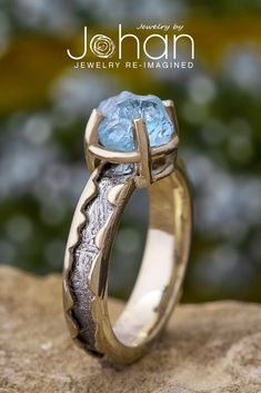 a gold ring with a blue topazte stone in the center on a rock