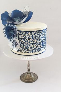 a blue and white decorated cake sitting on top of a metal plate with a silver stand