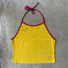 Life is a series of falling stars. Yellow halter crop top with fuchsia trim 95% cotton 5% spandex Soft and stretchy Custom bedazzled in the U.S.A., please allow for 3 additional days for production. This top is stretchy! For half sizes, we recommend that you downsize. Size S typically fits bust 30/32, waist 24/25. Y2k Cotton Halter Sleeveless Top, Y2k Halter Neck Cotton Top, Stretch Cotton Halter Neck Crop Top, Party Cotton Halter Neck Top, Stretch Cotton Halter Top For Festival, Cotton Halter Neck Top For Party, Y2k Halter Neck Crop Top For Festival, Stretch Cotton Halter Neck Top, Cotton Stretch Halter Neck Top