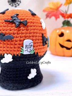 a crocheted halloween hat with bats and pumpkins around it on a table