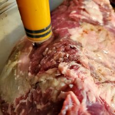 a large piece of meat sitting inside of a white bowl next to a yellow object