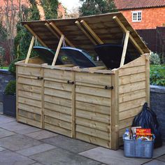 a large wooden storage box sitting on the side of a road next to a building