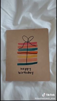 a happy birthday card with a gift wrapped in a ribbon on top of it and the words happy birthday