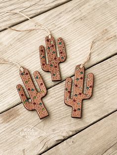 three wooden cactus ornaments hanging from string on wood planks with string attached to them