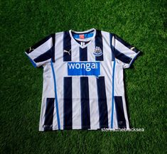 a soccer jersey laying on the grass with words wonga written in blue and white