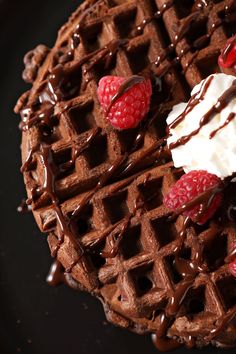 chocolate waffles topped with whipped cream and raspberries