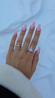 a woman's hand with pink nail polish and diamond rings on her fingers, against a white background