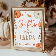 a sign that says gifts and cards in front of some pumpkins on the table