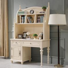 a white desk with a lamp next to it and bookshelf in the corner