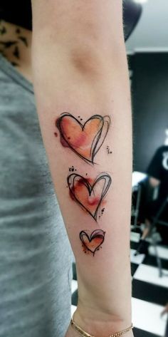 a woman's arm with three hearts tattooed on the left side of her arm