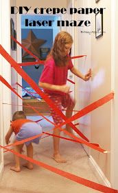 two children are playing with red tape in the hallway