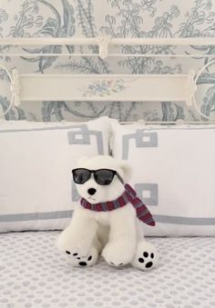 a white stuffed bear wearing sunglasses on top of a bed